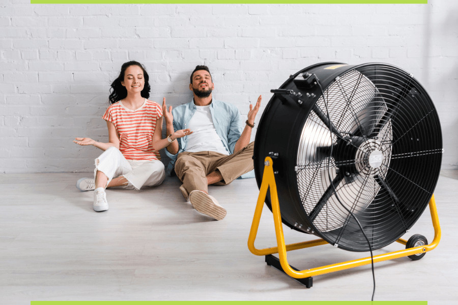 Wentylator stojący, a obok dwójka ludzi cieszących się z chłodnego powietrza